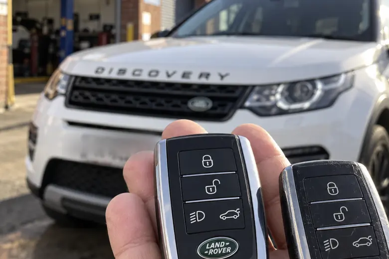 A car key held in front of a Land Rover Discovery Sport