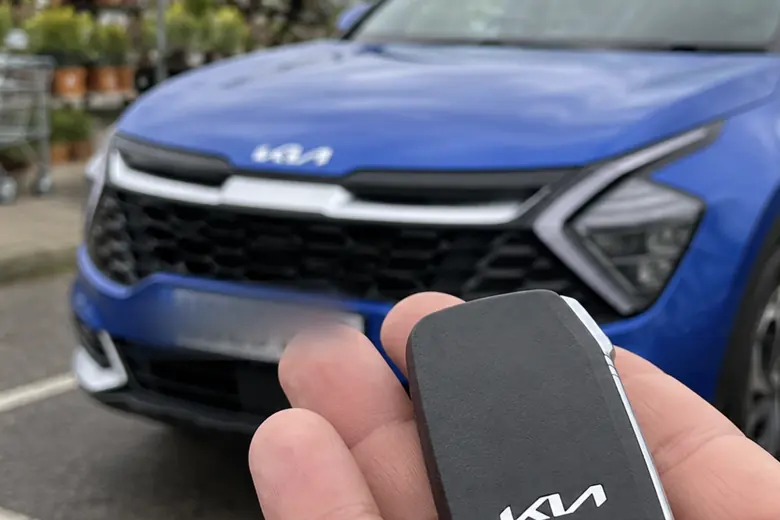 A car key held in front of a Kia Sportage