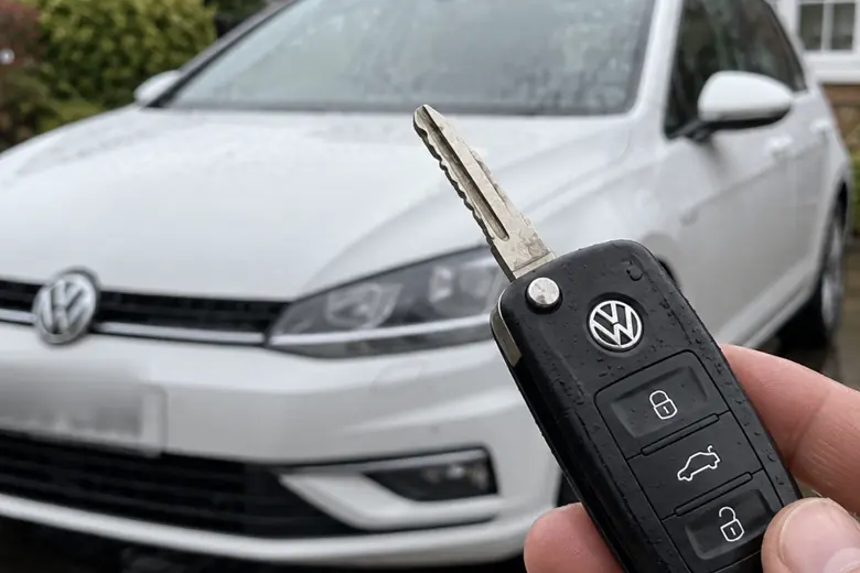 A car key held in front of a Volkswagen Golf